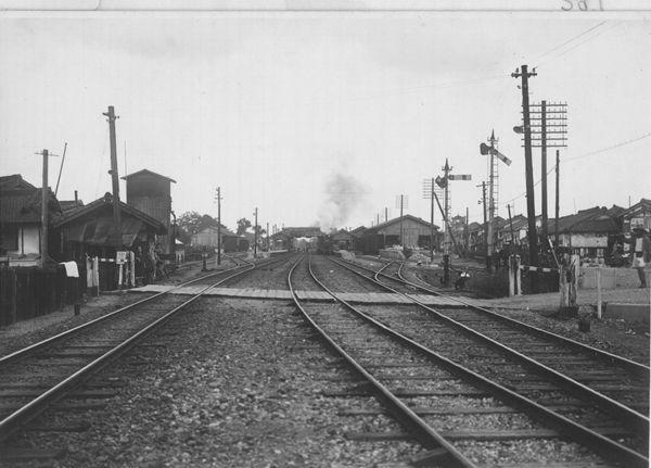 駅構内の線路を横切る踏切が写された白黒写真