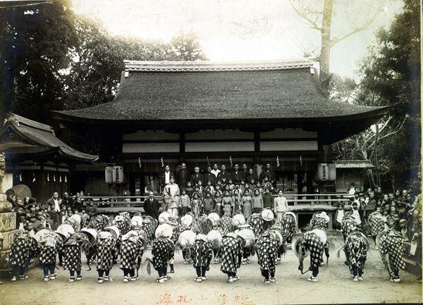 拝殿所に紋付き袴の男性や着物姿の子供たちが並び、境内で舞を舞った人たちが頭を下げている白黒写真
