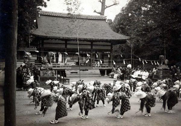 神社の境内で豊年舞をしている人達の白黒写真
