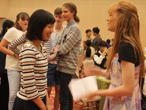 リズモー市の女子学生と日本の学生が対面で会話している後ろで他のリズモー市の学生が会話している写真