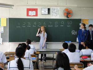 リズモー市の女子学生が黒板に書いた数字を指さしているのを見ている中学生の写真