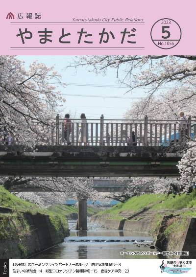 広報誌5月号表紙  桜が満開の高田川畔からネーミングライツ募集中の高田橋を南から北に望むようす