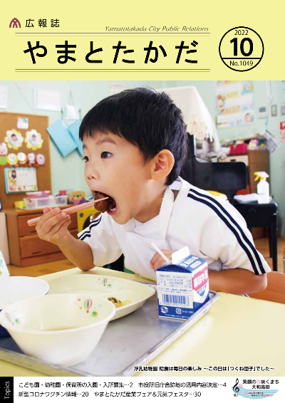 広報誌10月号表紙  浮孔幼稚園の給食にて、男の子が大きな口を開けて「つくね団子」を口に運ぶようす