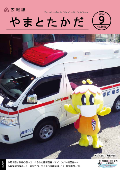 広報誌9月号表紙 救急車の前でマスクをした大和高田市のマスコットキャラクター「みくちゃん」が両手を広げて立っている写真