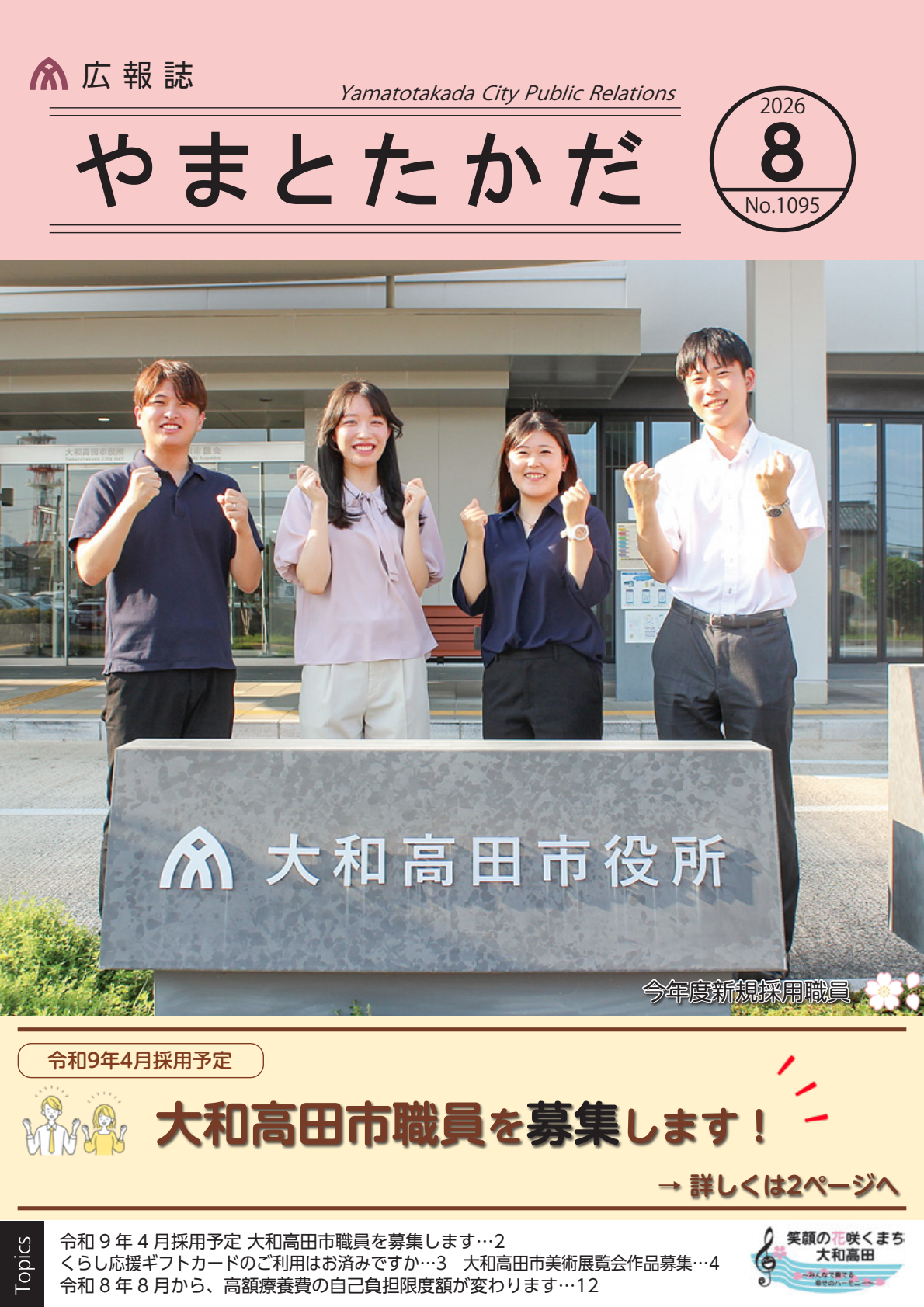 大和高田市役所の正面玄関前。「大和高田市役所」と刻まれた石碑の後ろで、両手でガッツポーズをする令和8年度新規採用職員4人。
